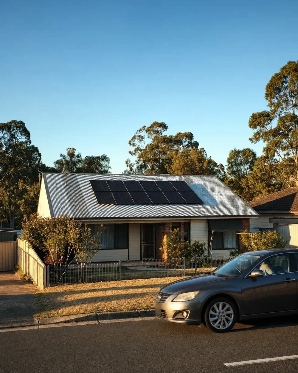 A Western Sydney house with a light corrugated metal roof carrying a neat grid of black solar panels