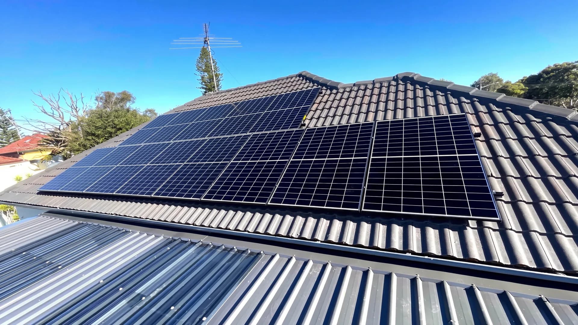 Solar panels installed across the tiled and metal roof of a suburban home